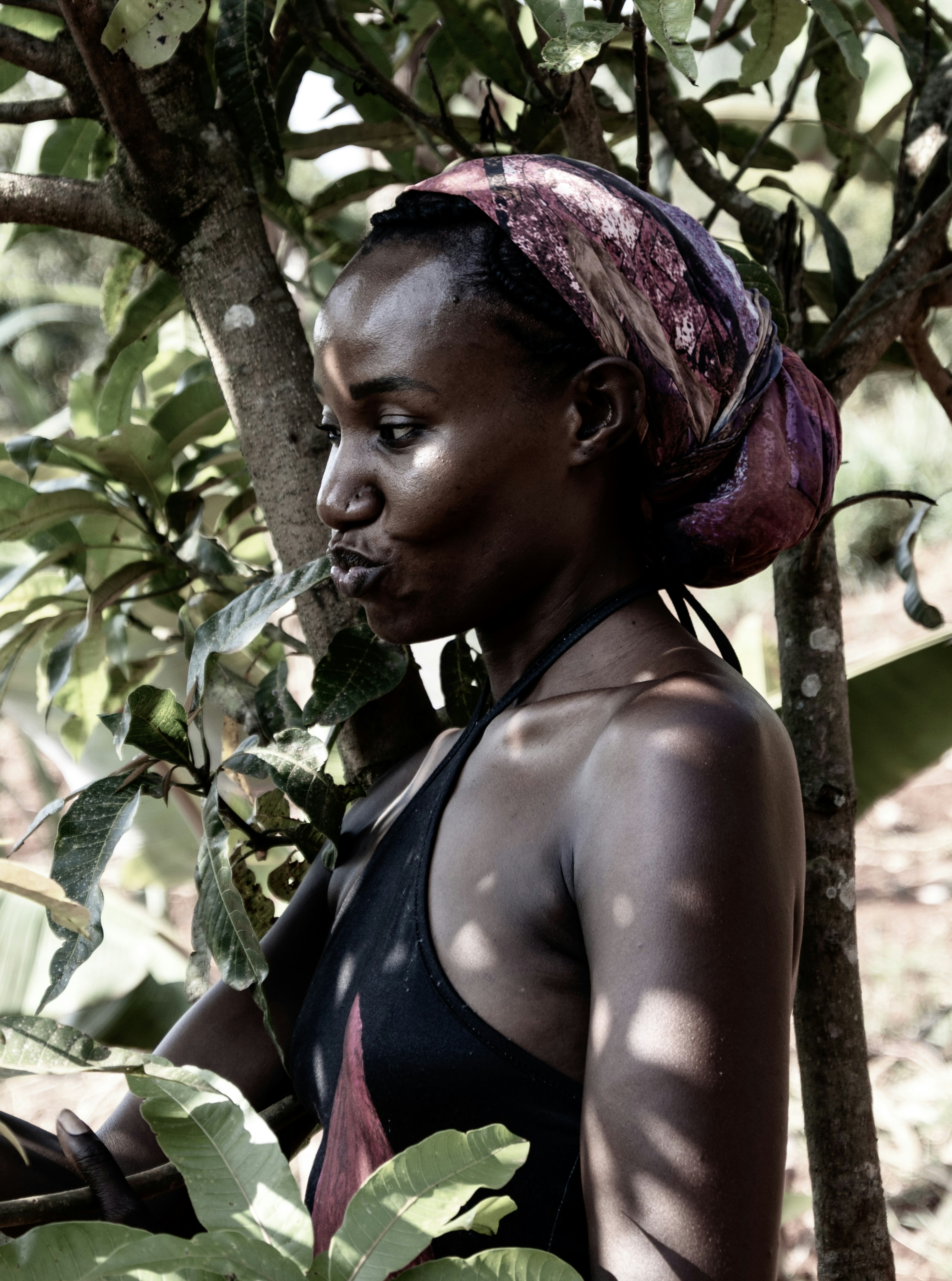 A woman in a black tank top is standing in a tree