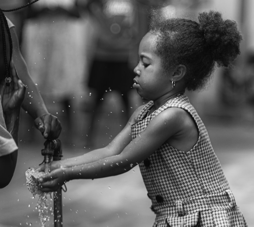 A little girl is playing with a fire hydrant