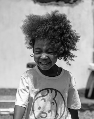 A young girl with an afro standing in front of a building