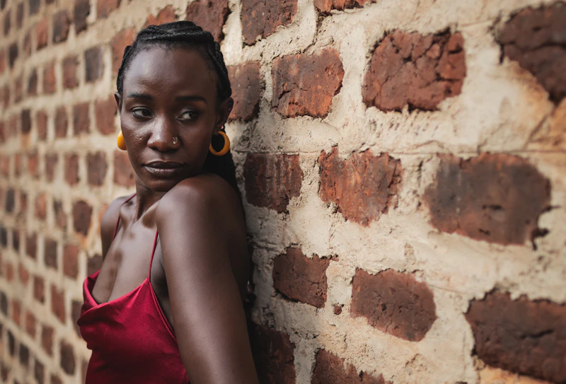 Woman leaning against a brick wall