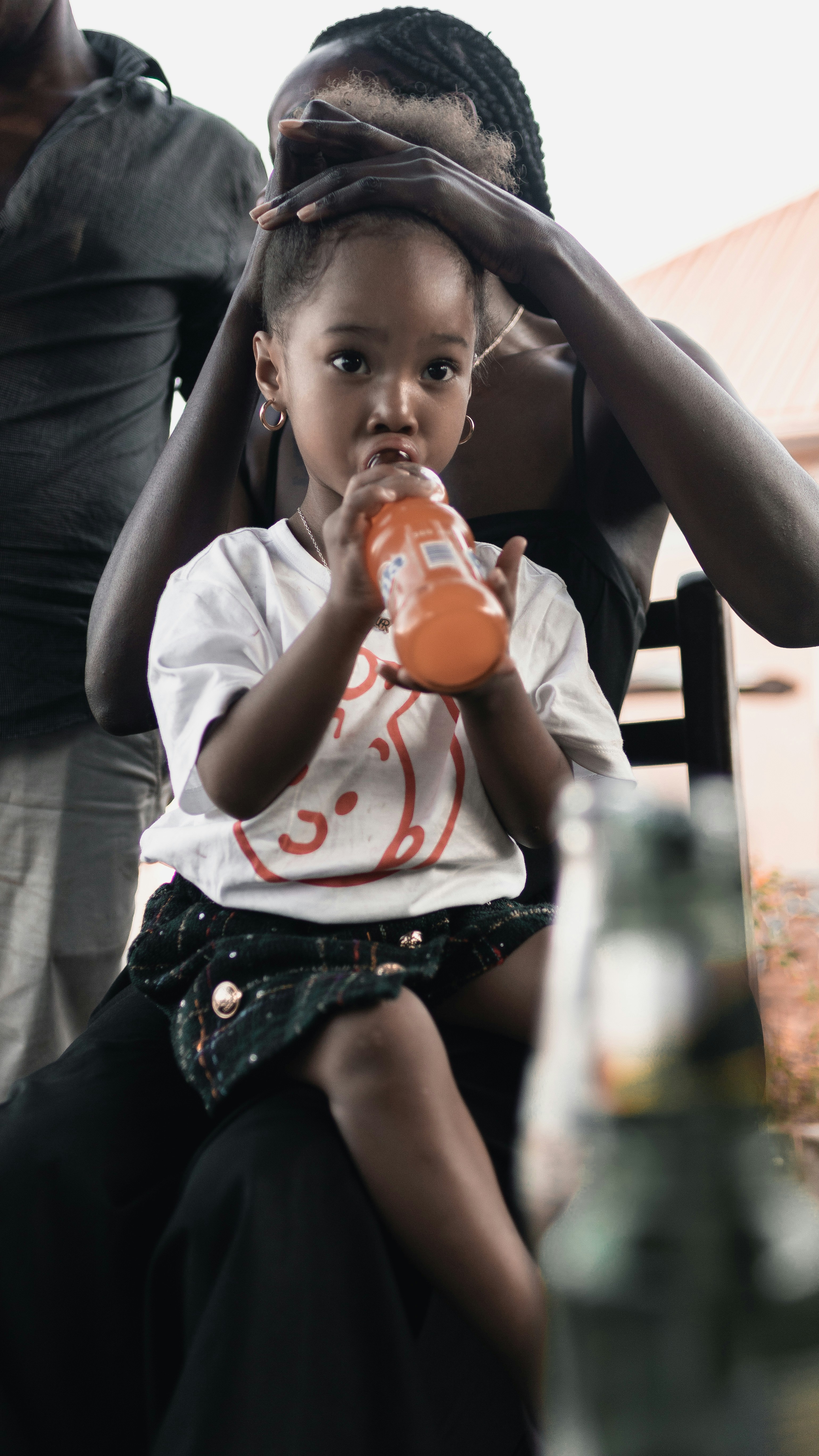 A little girl sitting on a bench drinking from a bottle
