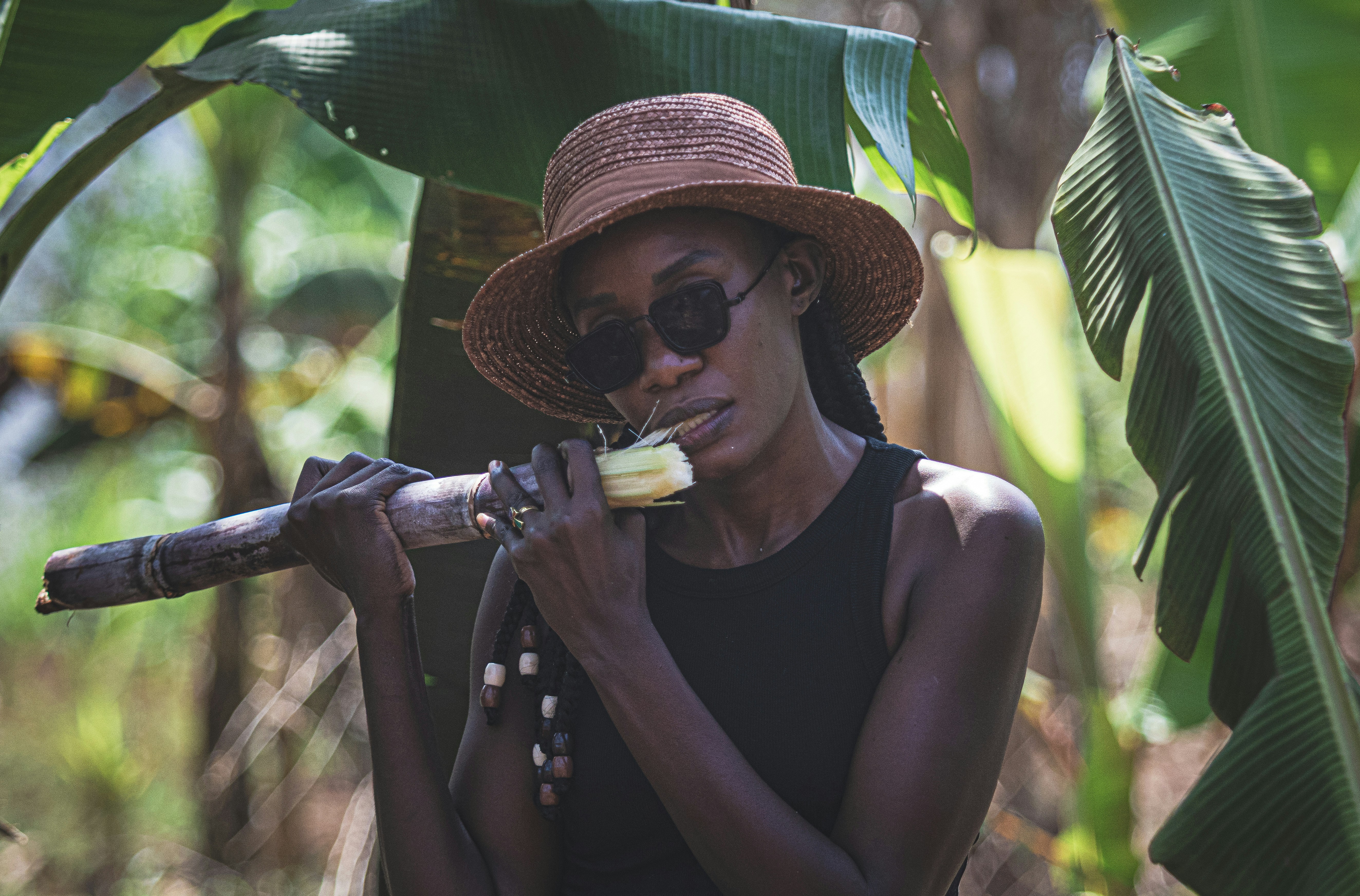 A woman in a hat and sunglasses is holding a stick