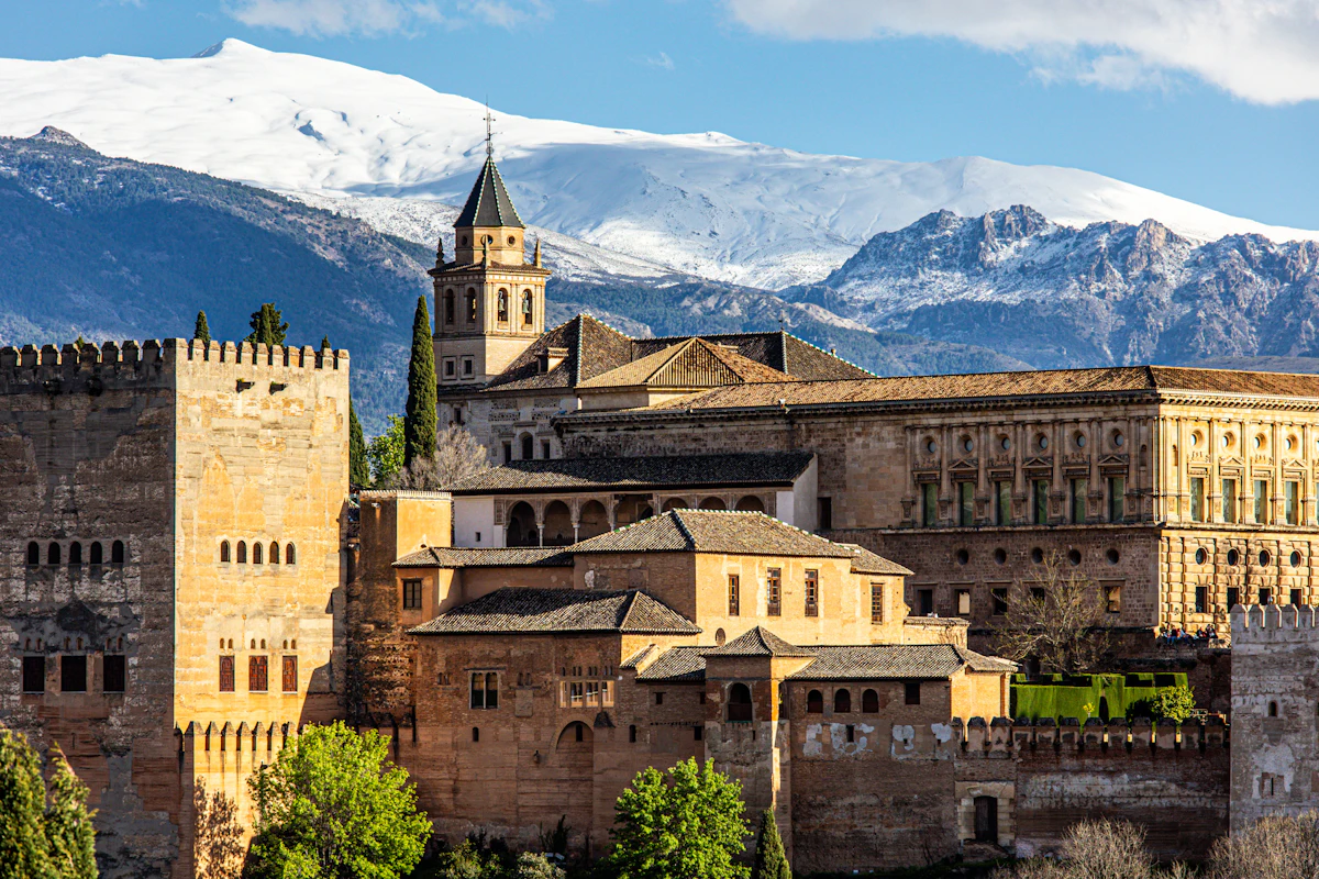The Alhambra's palaces and bell tower in Granada, with snow-covered peaks behind