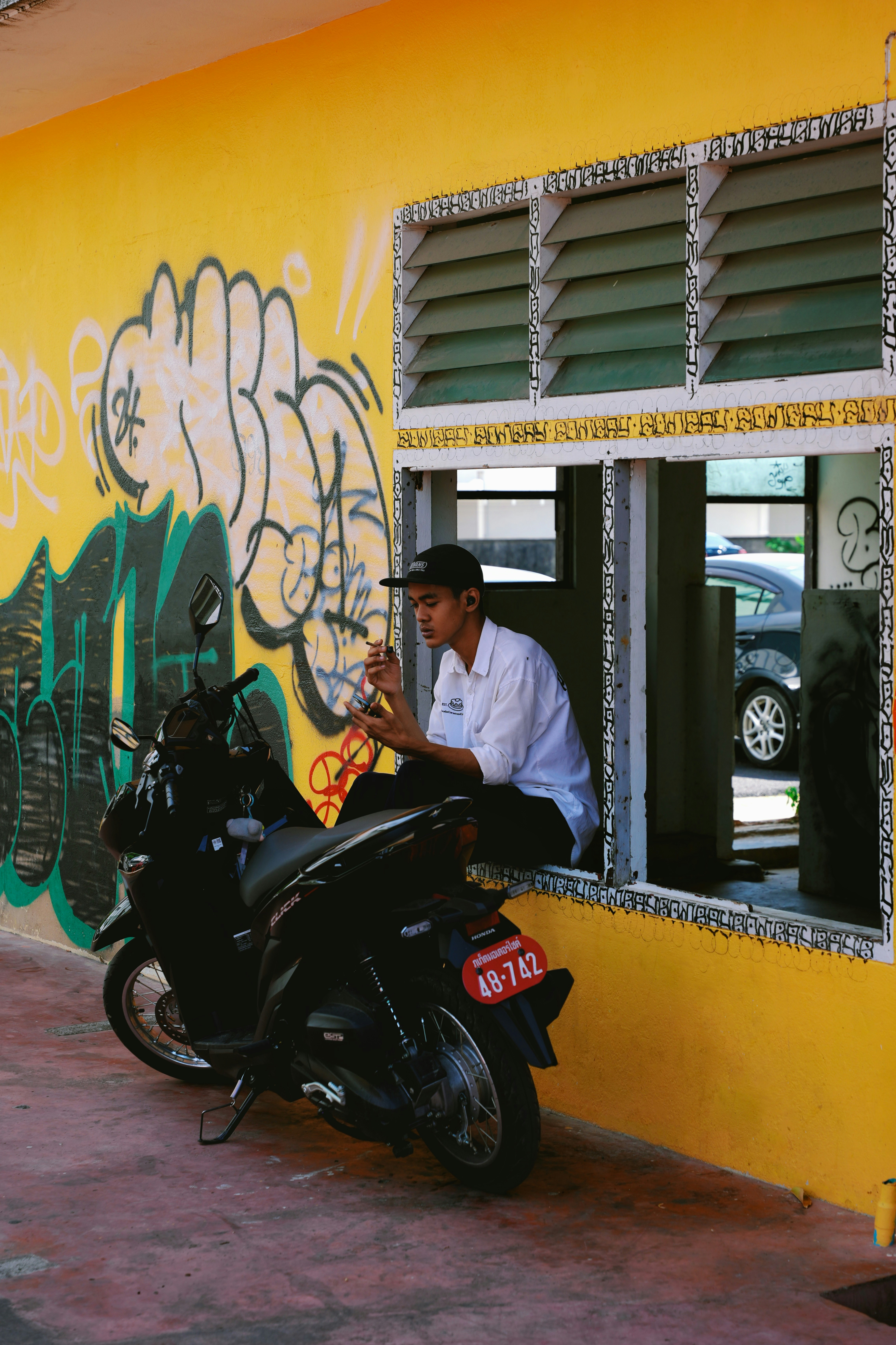 Seorang pria duduk di atas sepeda motor di depan sebuah gedung