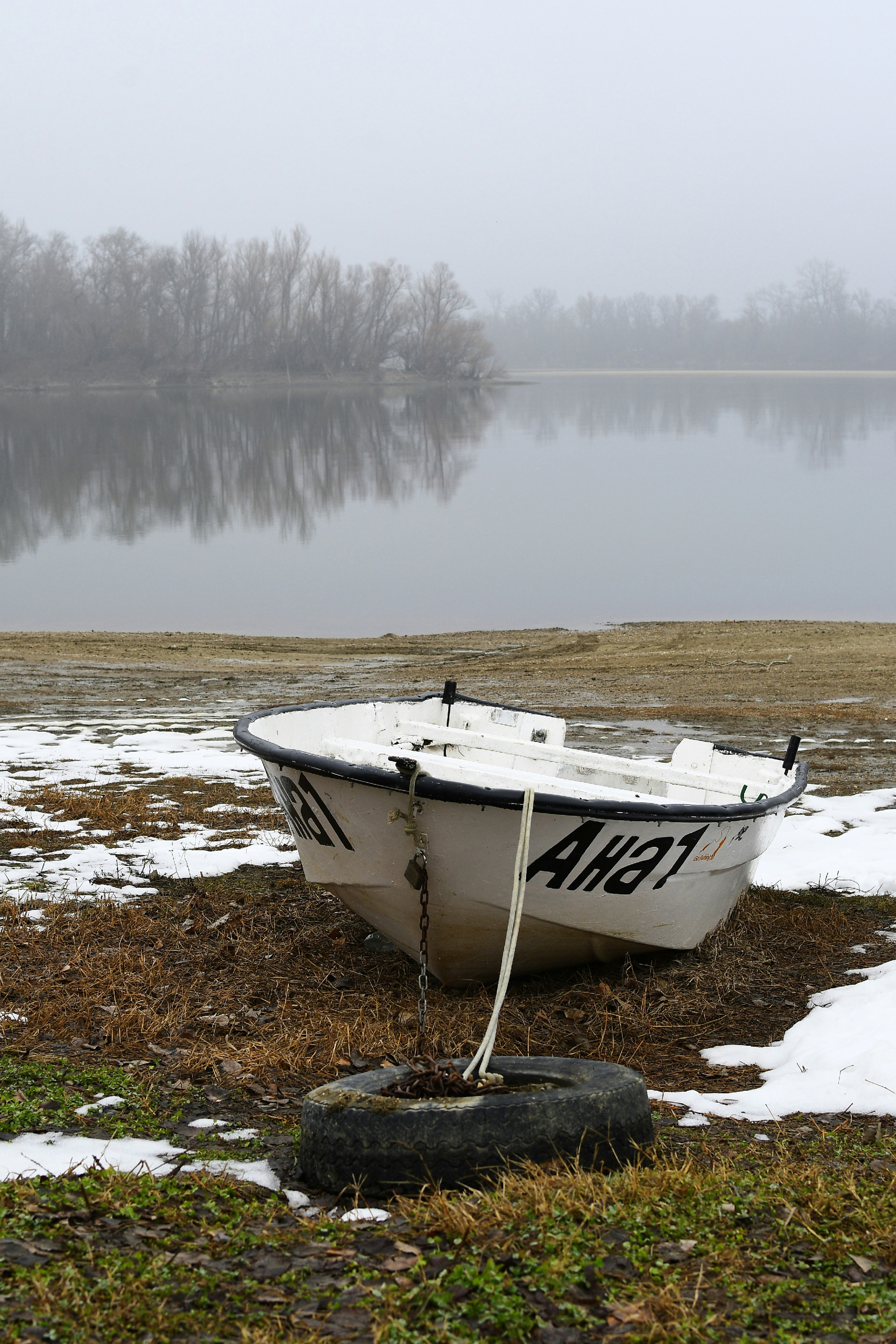 A white boat sitting on top of a grass covered field