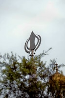 A clock tower with a weather vane on top of it