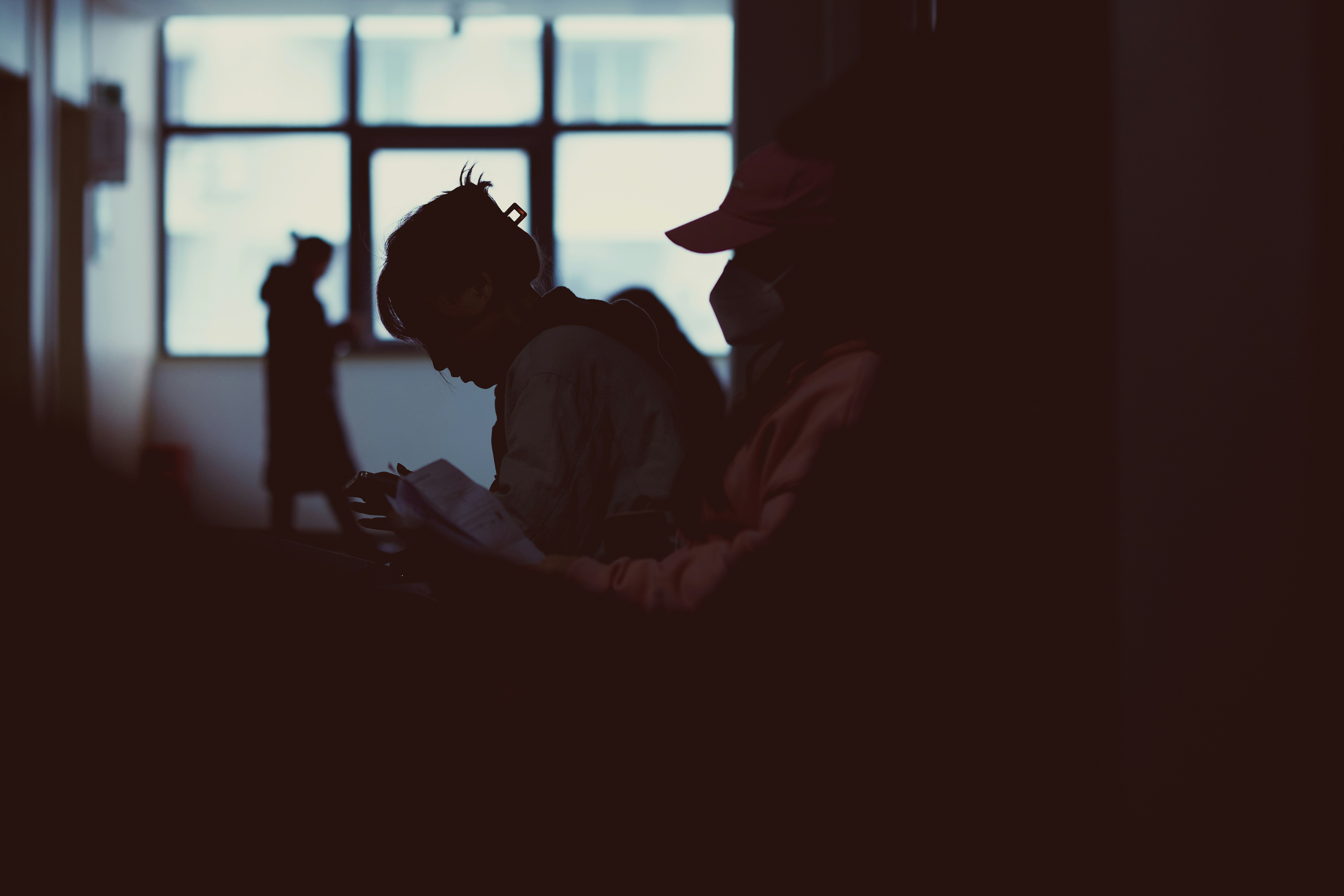 Two people sitting in a dark room with a window