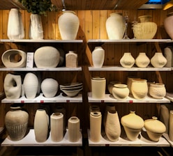 A shelf filled with lots of white vases
