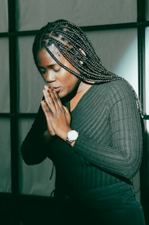 A woman standing in front of a window praying