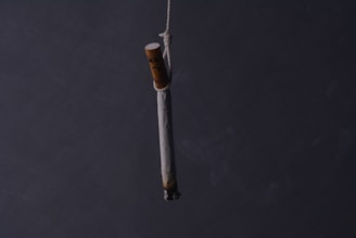 A burning cigarette is hanging by a string.