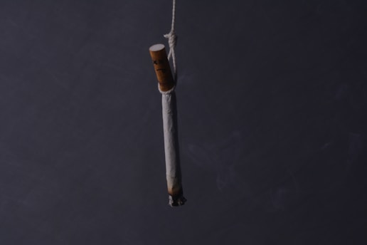 A burning cigarette is hanging by a string.