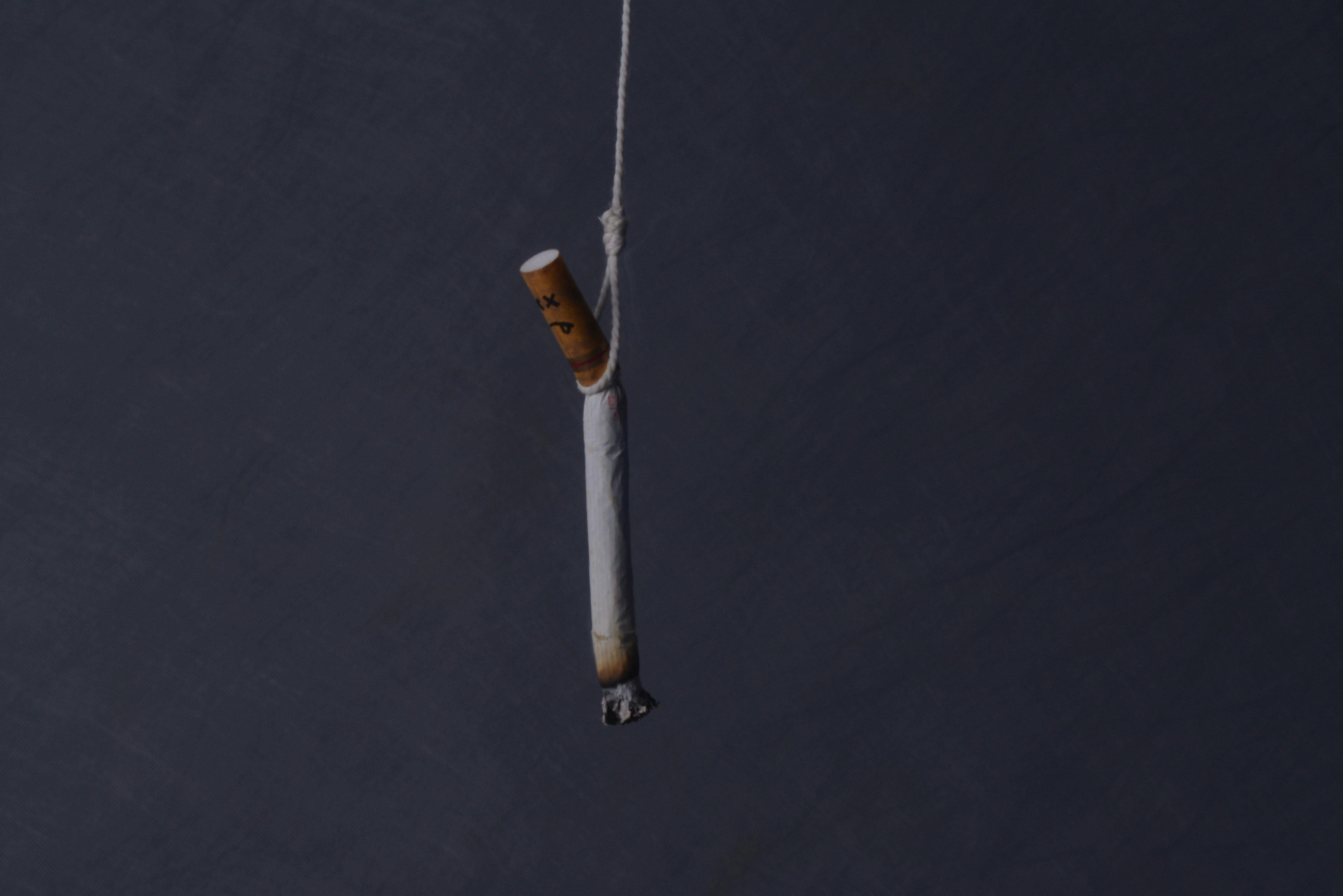 A cigarette is hung on a fishhook.
