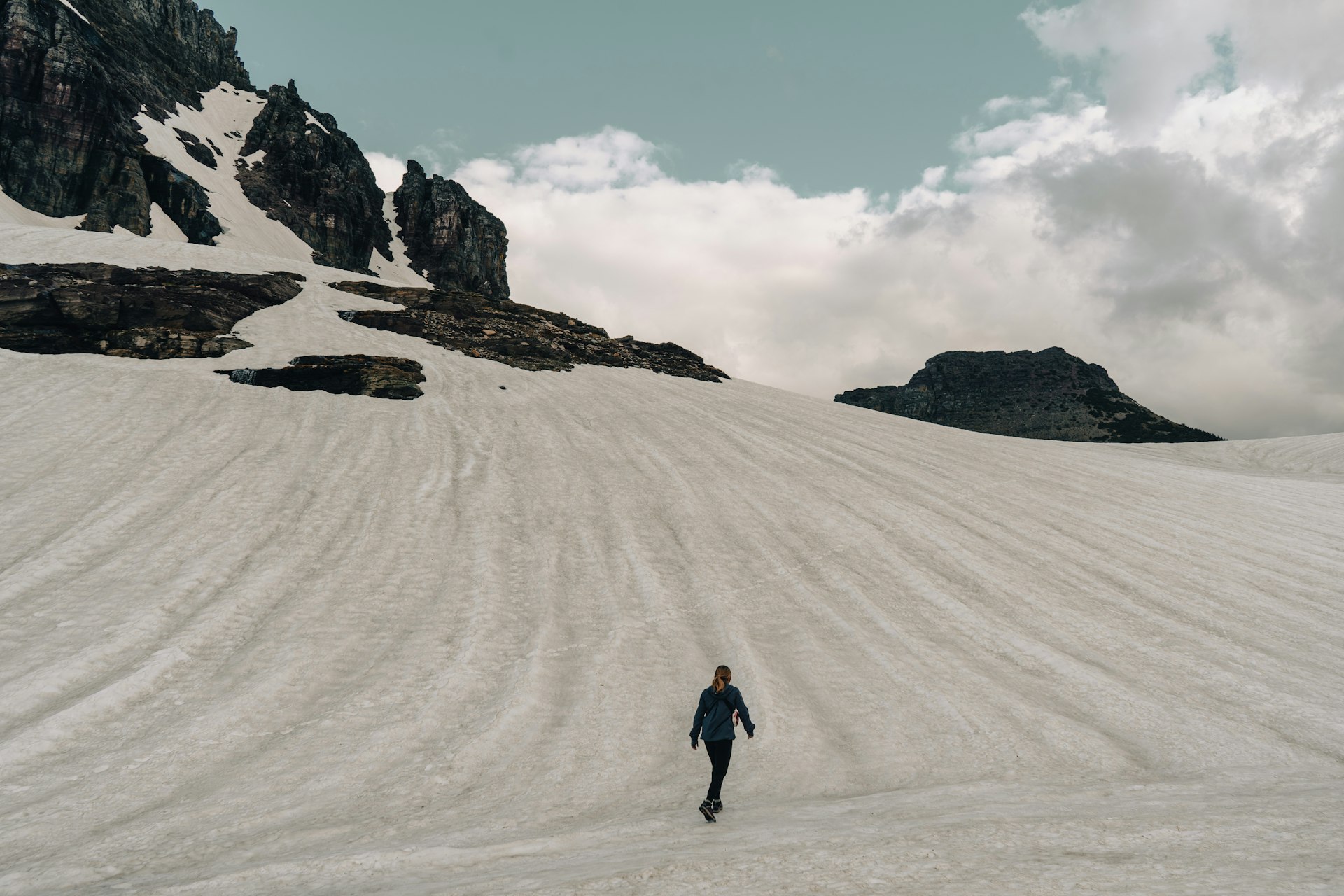 Person walks across a snowy mountain landscape.
