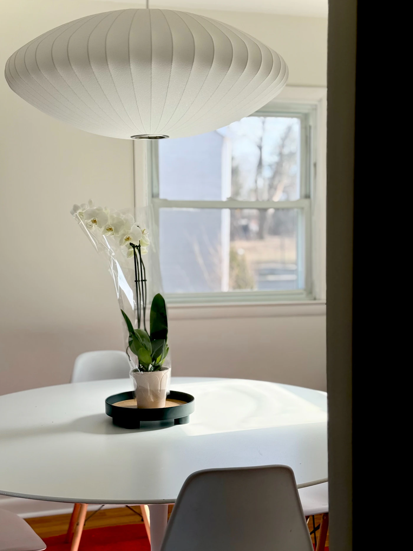 Sculptural white pendant light above a contemporary dining table in a softly illuminated interior