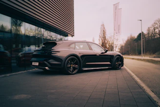 A black porsche parked outside a modern building.