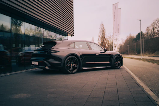 A black porsche parked outside a modern building.