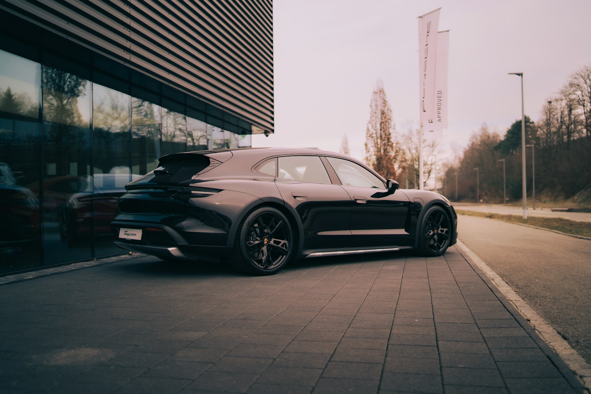 A black porsche parked outside a modern building.