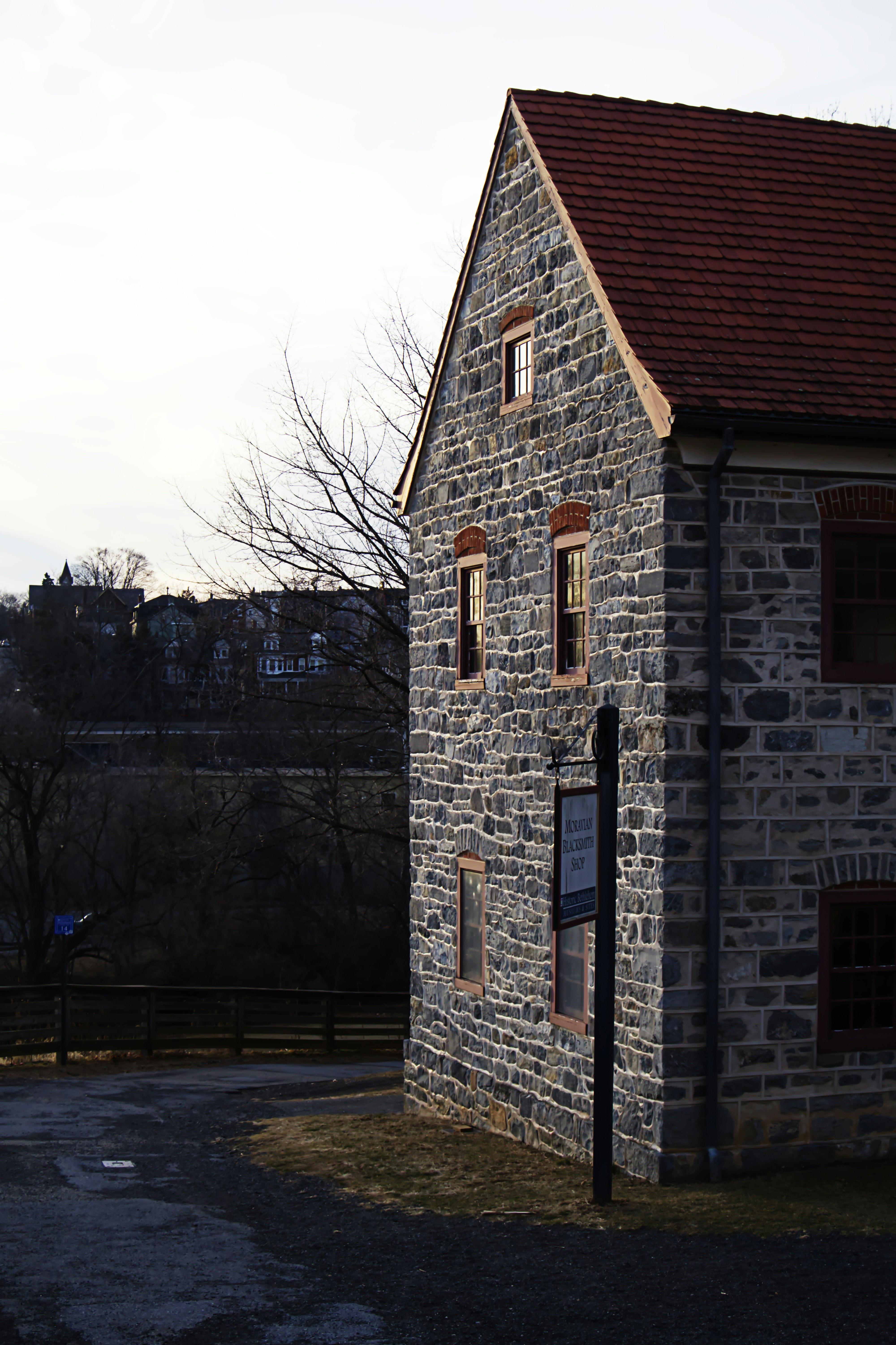 Ein Steinhaus steht mit rotem Dach an der Ecke.