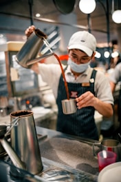 Barista is pouring coffee into a mug.