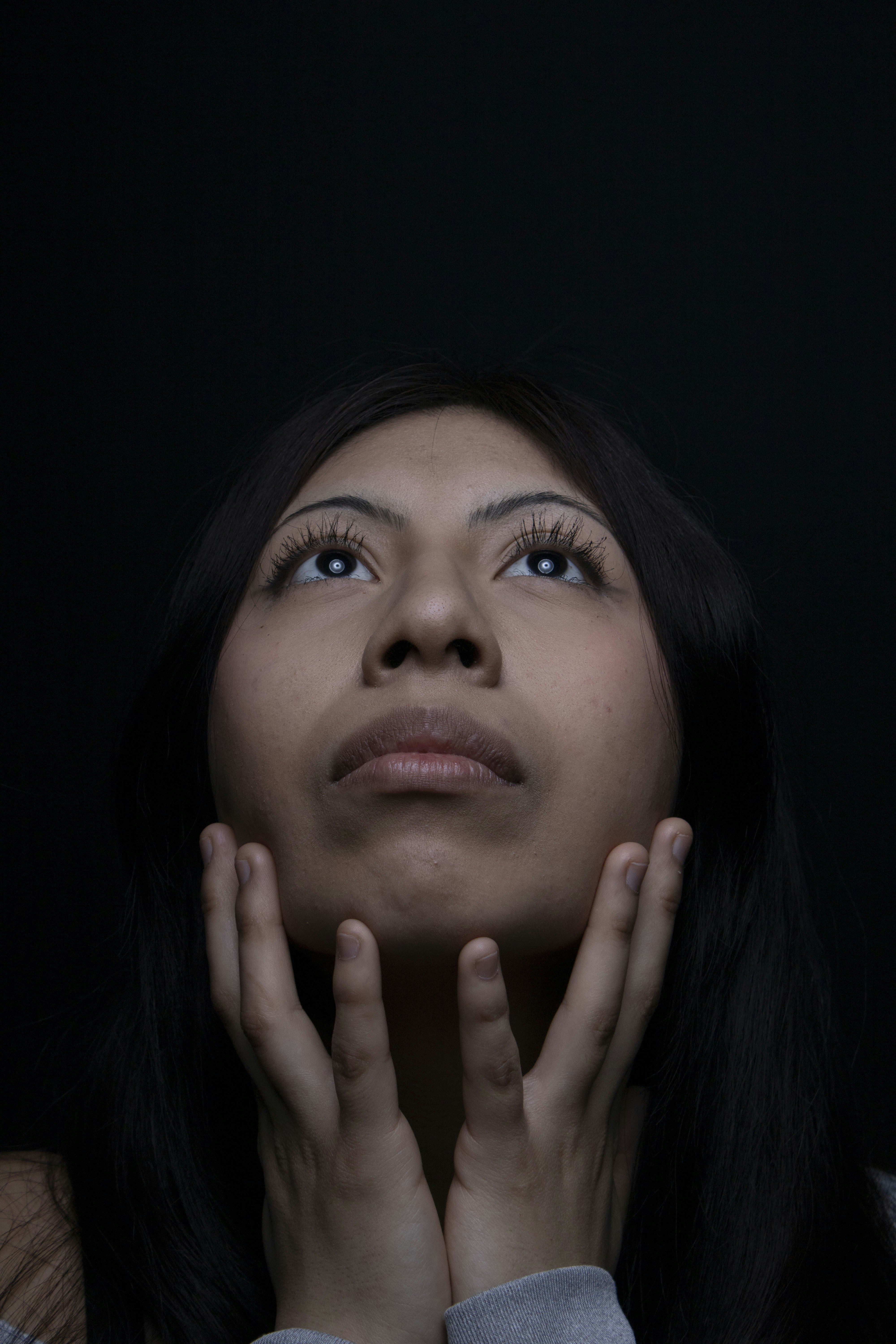 Woman looking upward with hands on her face