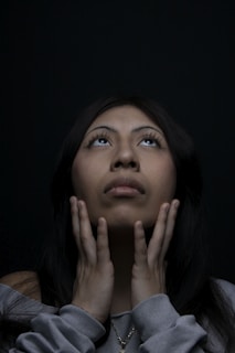 Woman looks up, hands near her face.