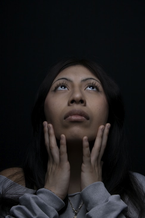 Woman looks up, hands near her face.