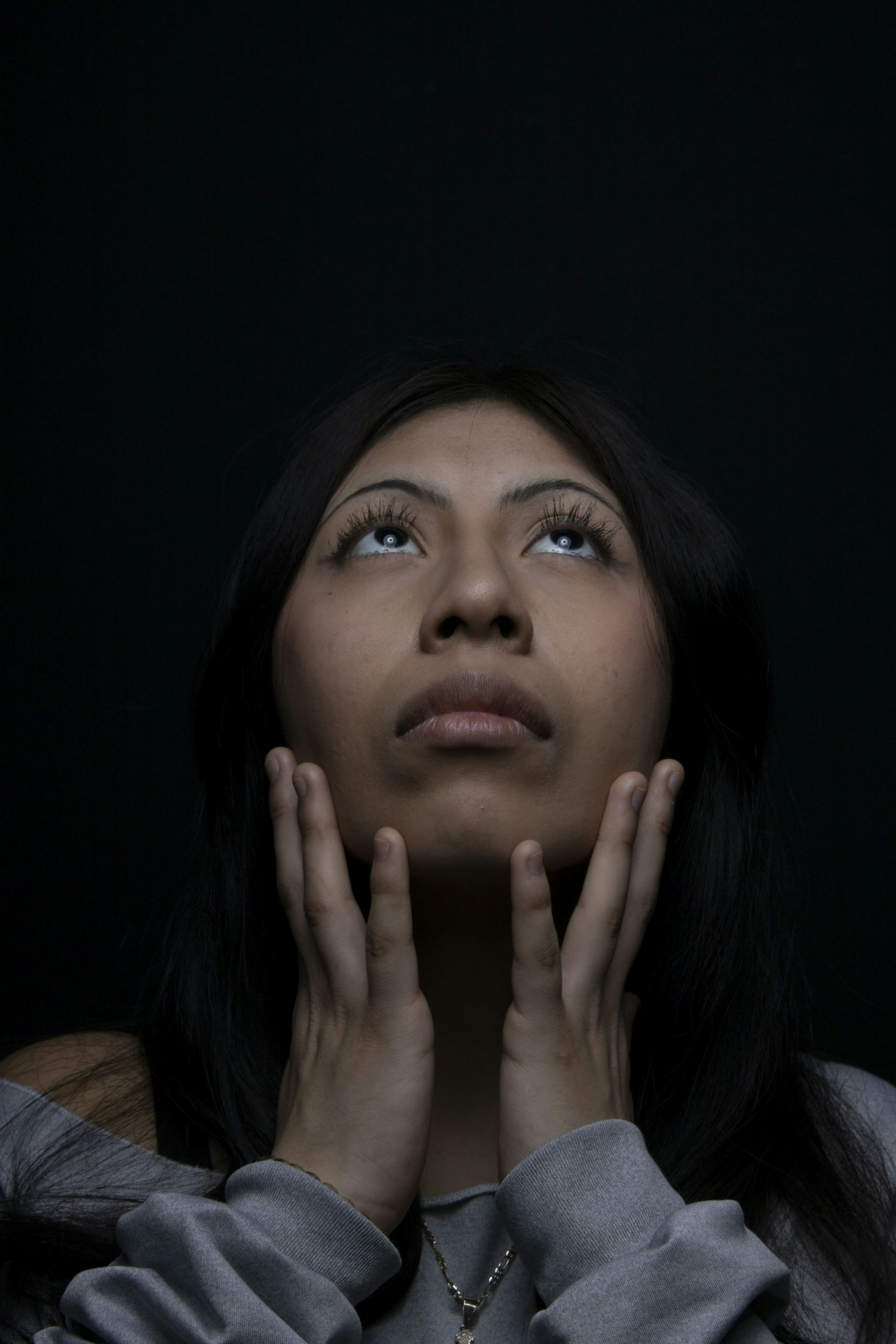 Woman looks up, hands near her face.