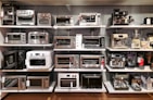 A room filled with lots of different types of microwaves