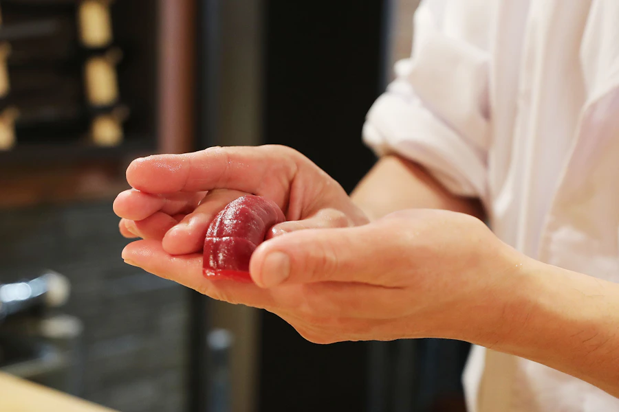 Chef holding a fresh piece of sashimi