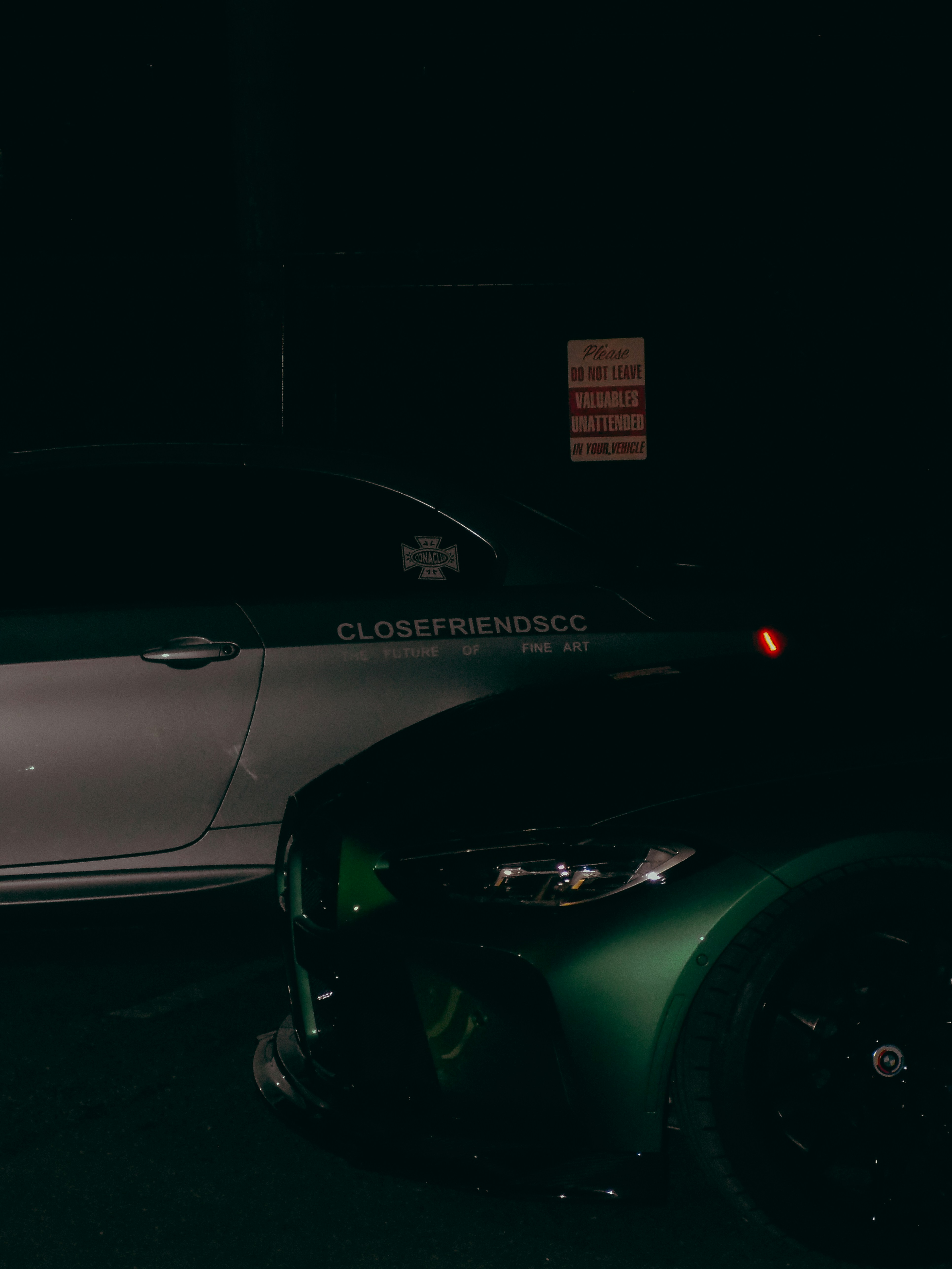 Two luxury cars parked outside at night.