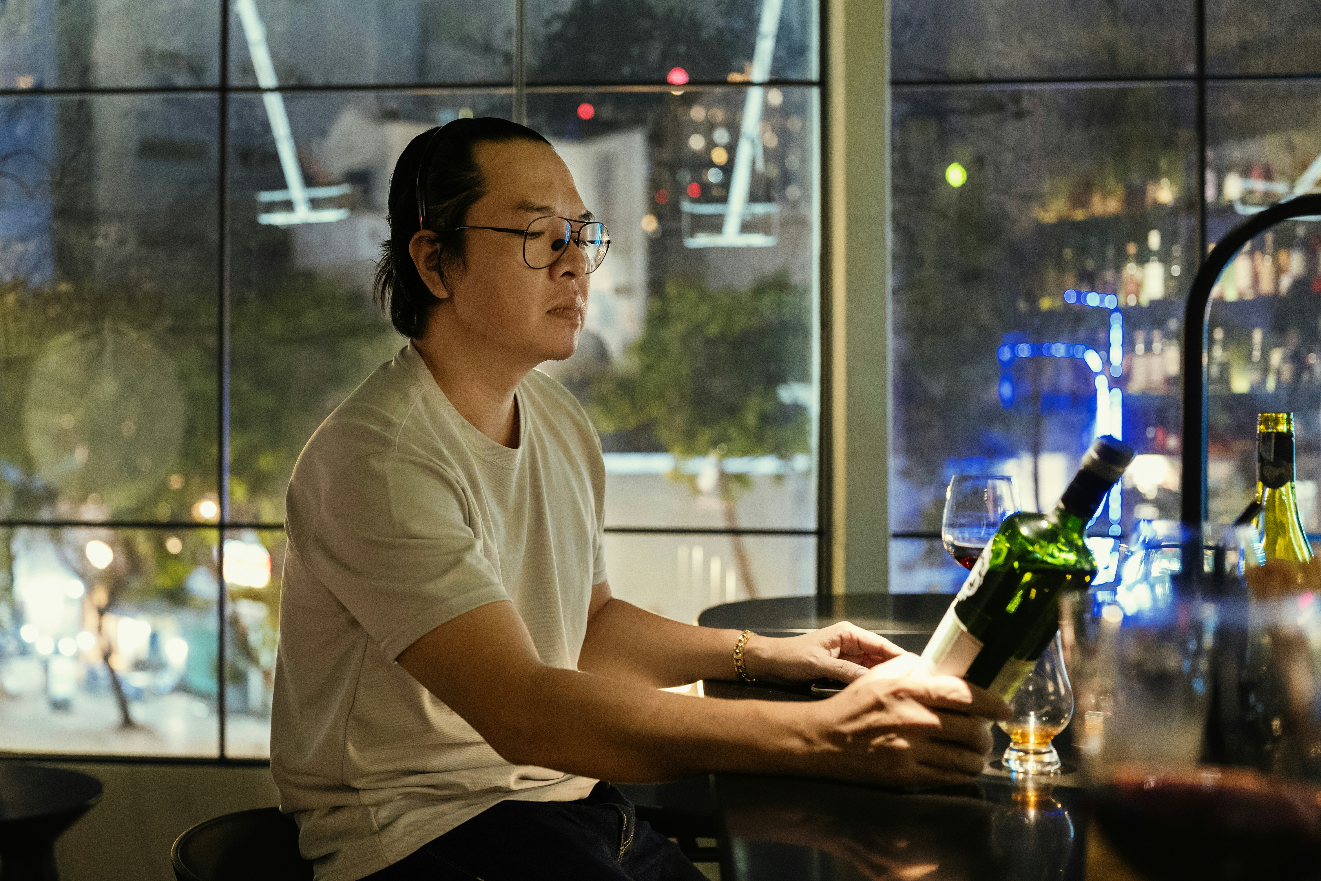 Man enjoys wine at a dimly lit bar.