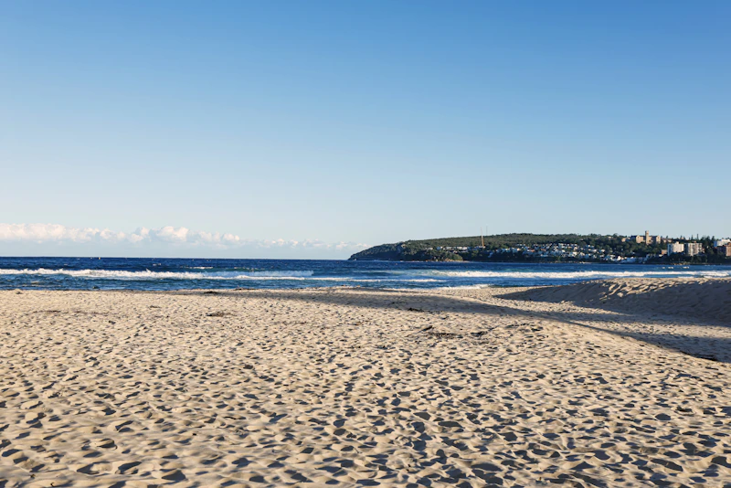 Manly Beach sandy shore with ocean waves under clear blue sky