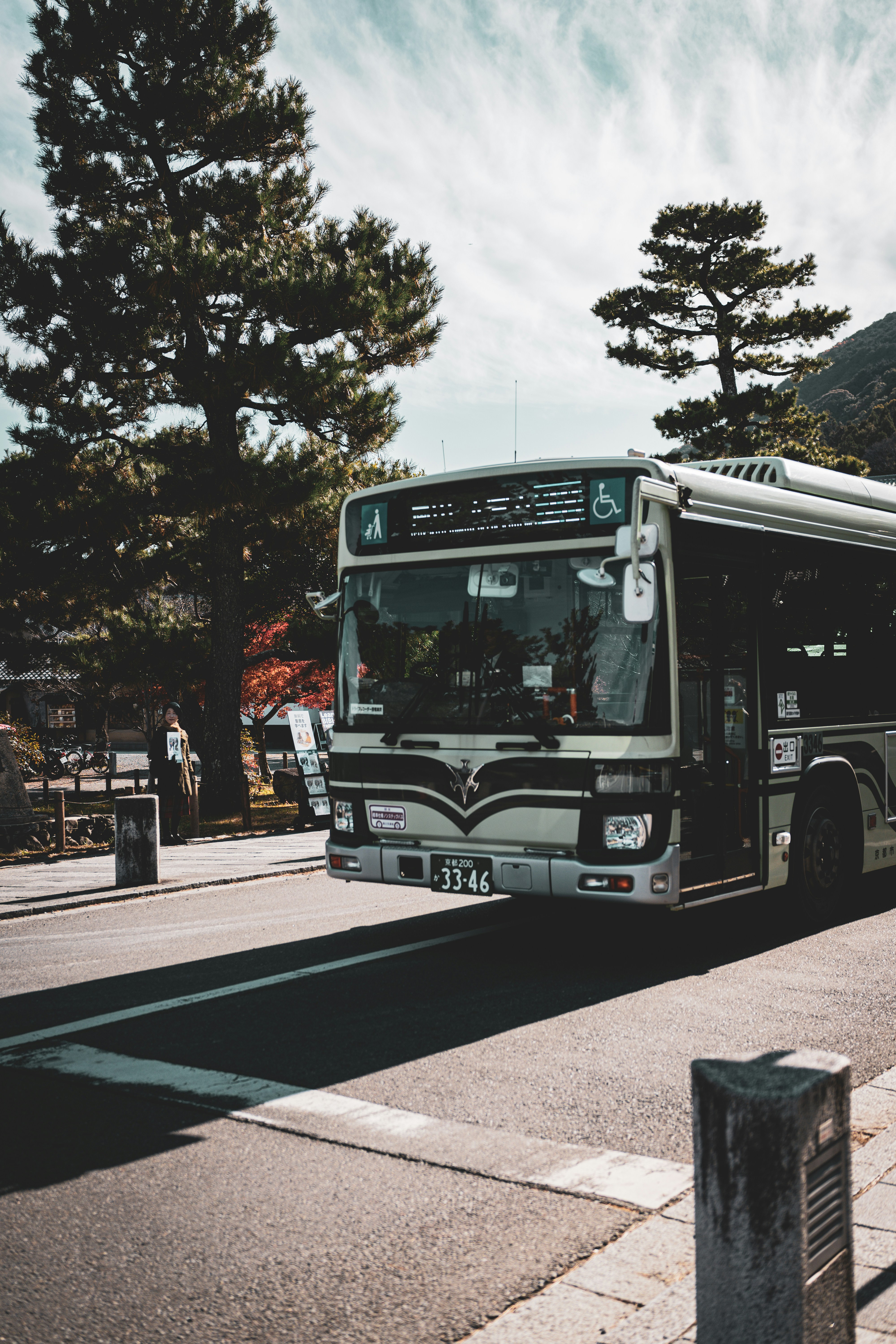 A Kyoto city bus in front of trees and mountains, representing local transportation options in Kyoto.