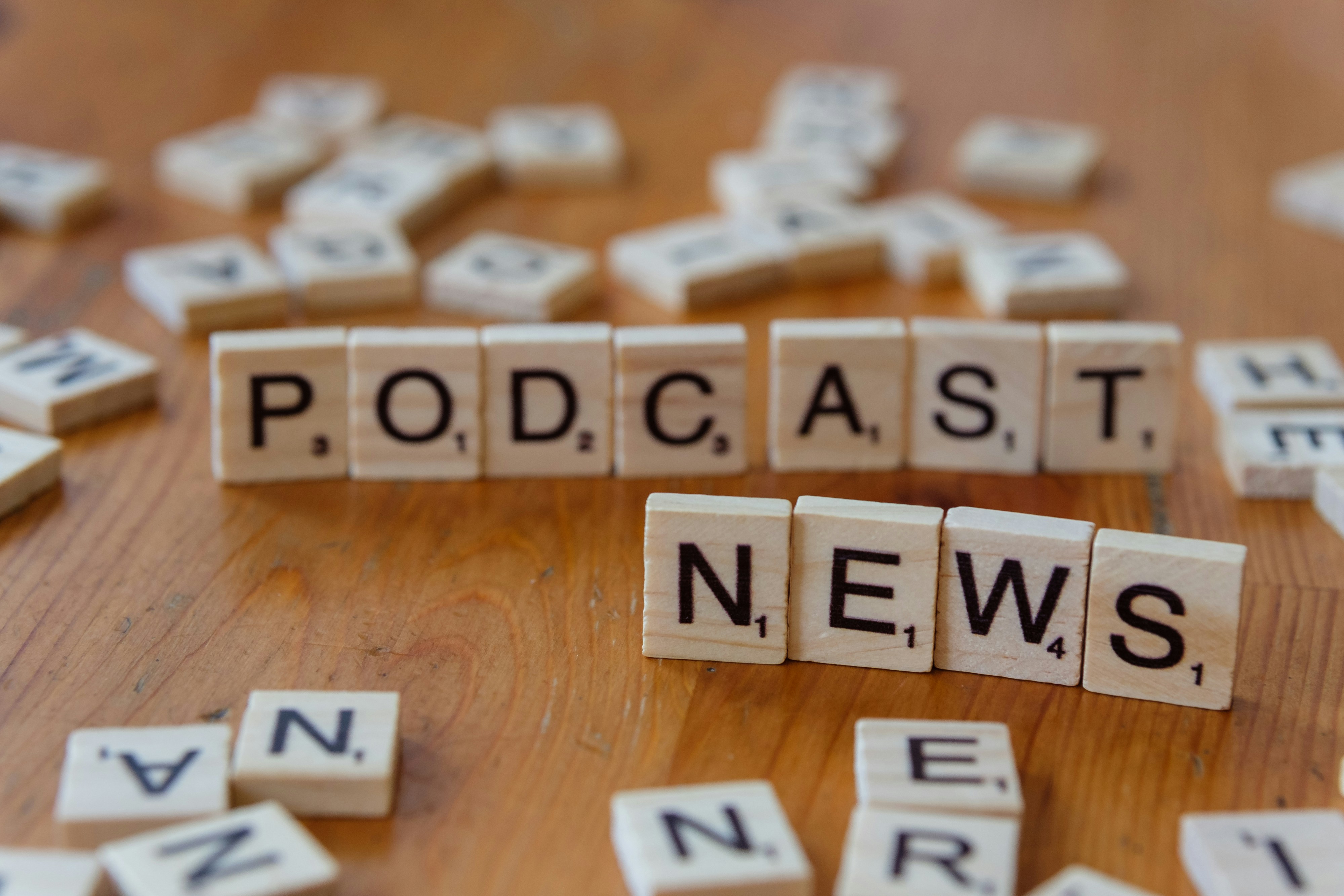 A wooden table topped with scrabble tiles spelling news