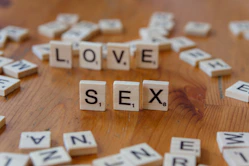 A wooden table topped with scrabble letters spelling love and sex