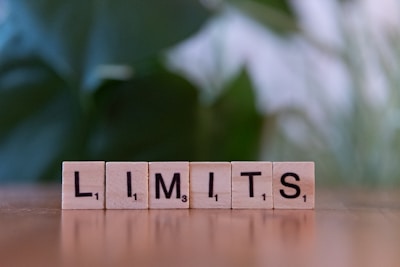 A wooden block spelling the word limits on a table