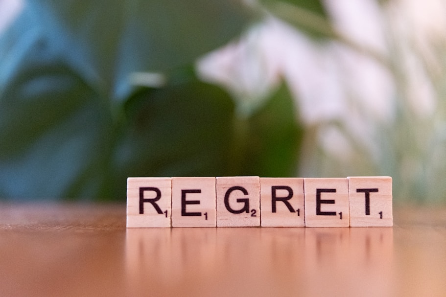 A scrabble block spelling the word regret on a table