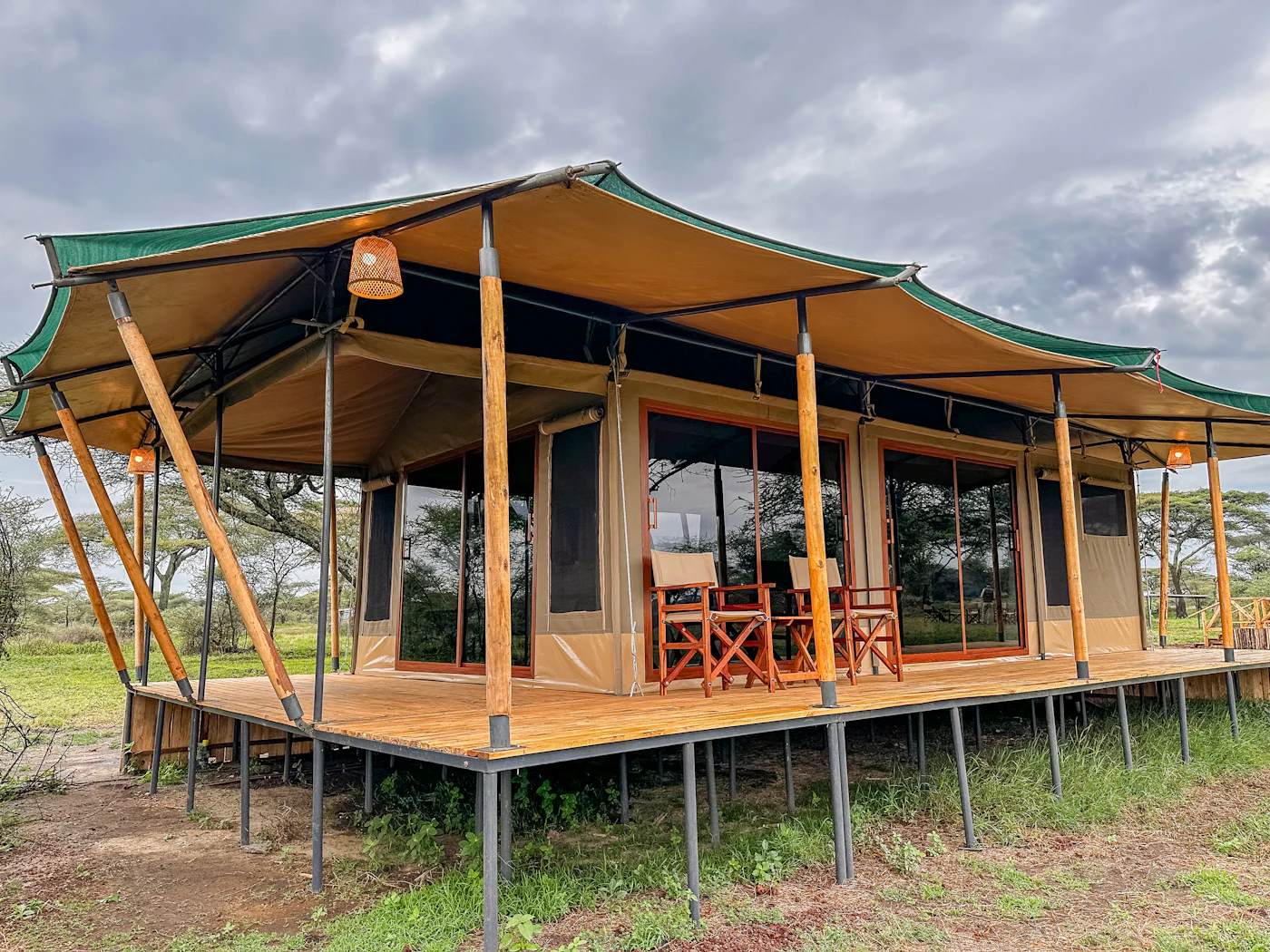 A canvas safari tent with a shaded porch set among trees