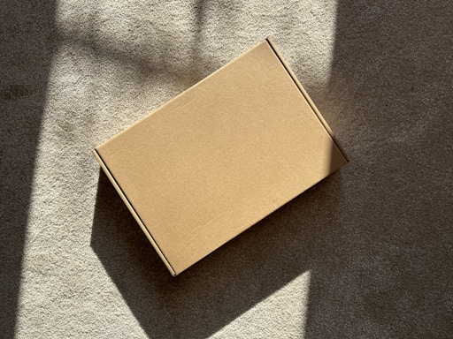 A cardboard box sits on a textured surface.