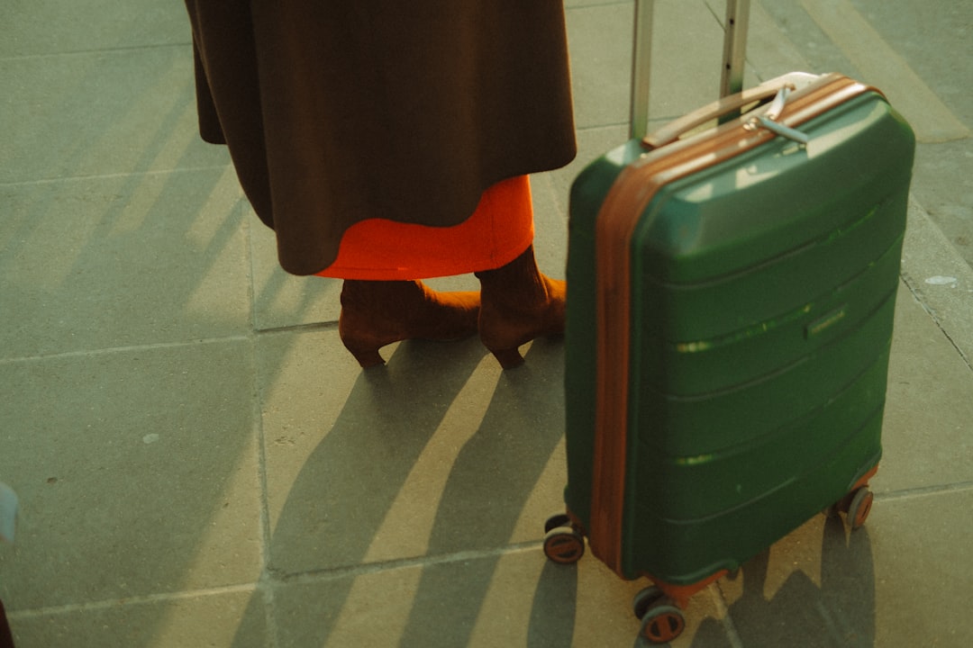 A woman standing next to a green suitcase,