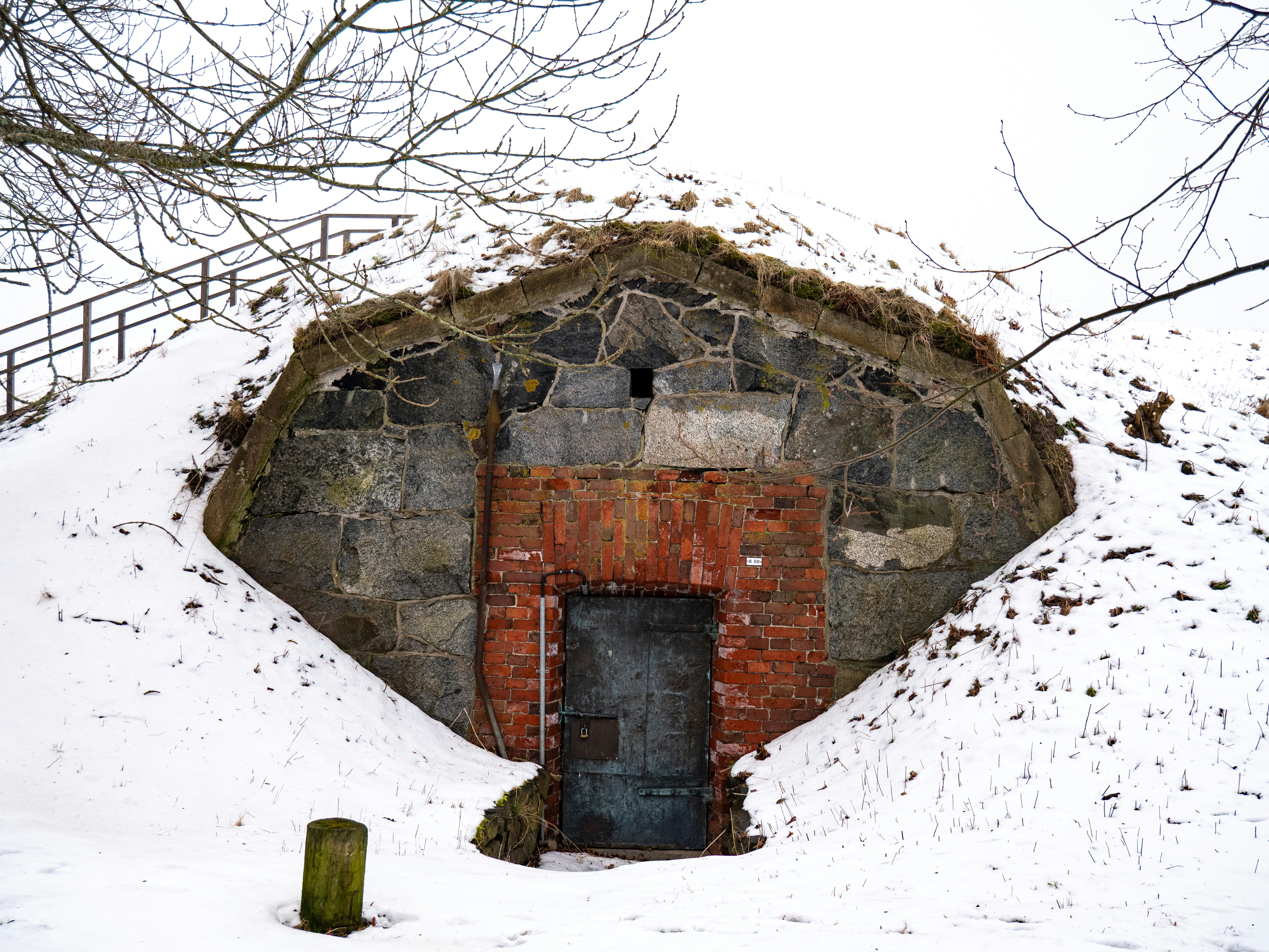 A stone building entrance surrounded by snow., 