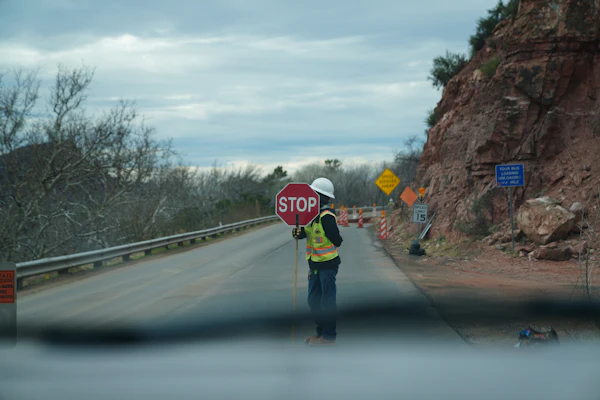 Traffic controller holding a stop sign on a highway