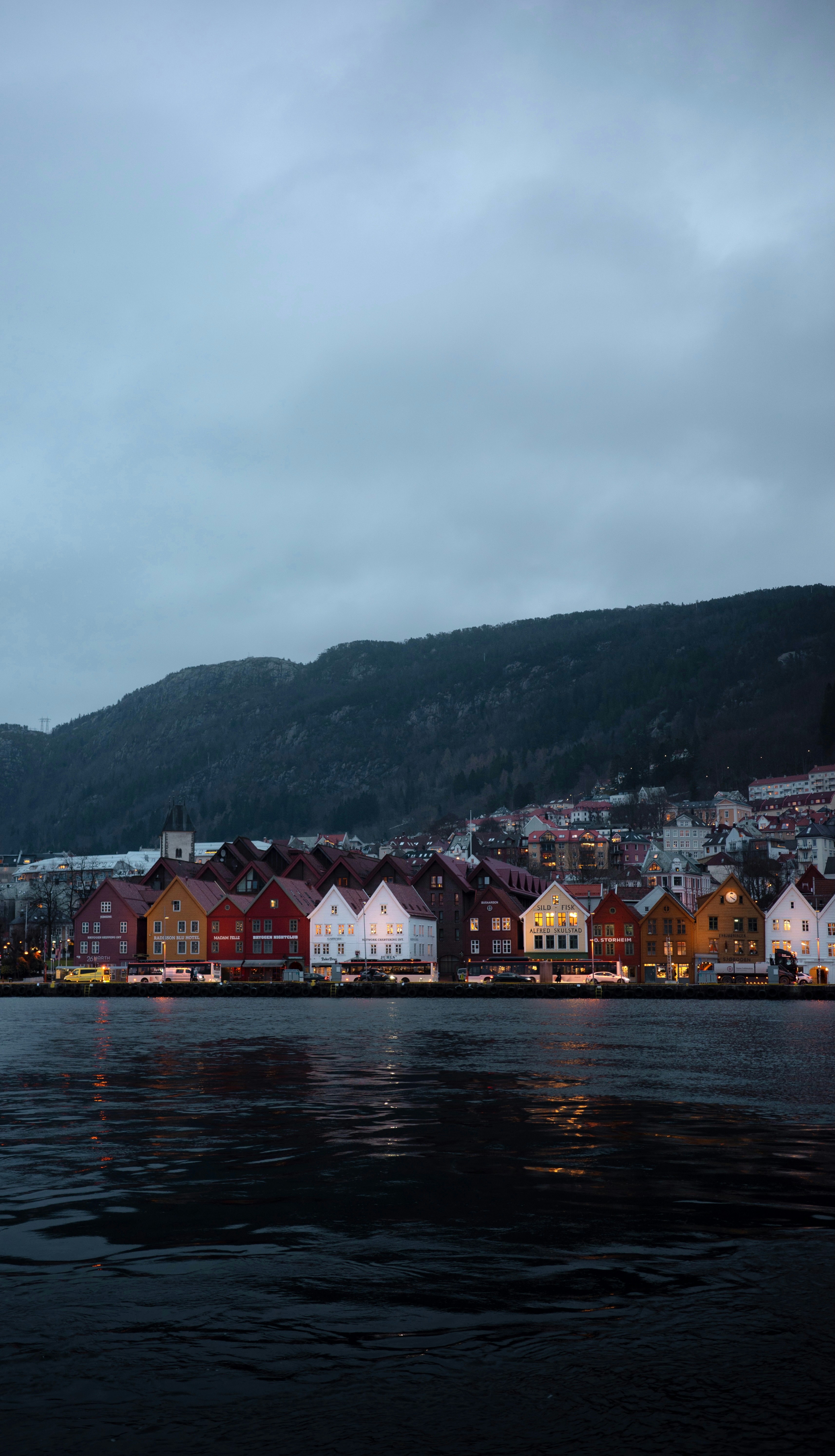 Bunte Gebäude säumen das Wasser unter einem wolkenverhangenen Himmel.