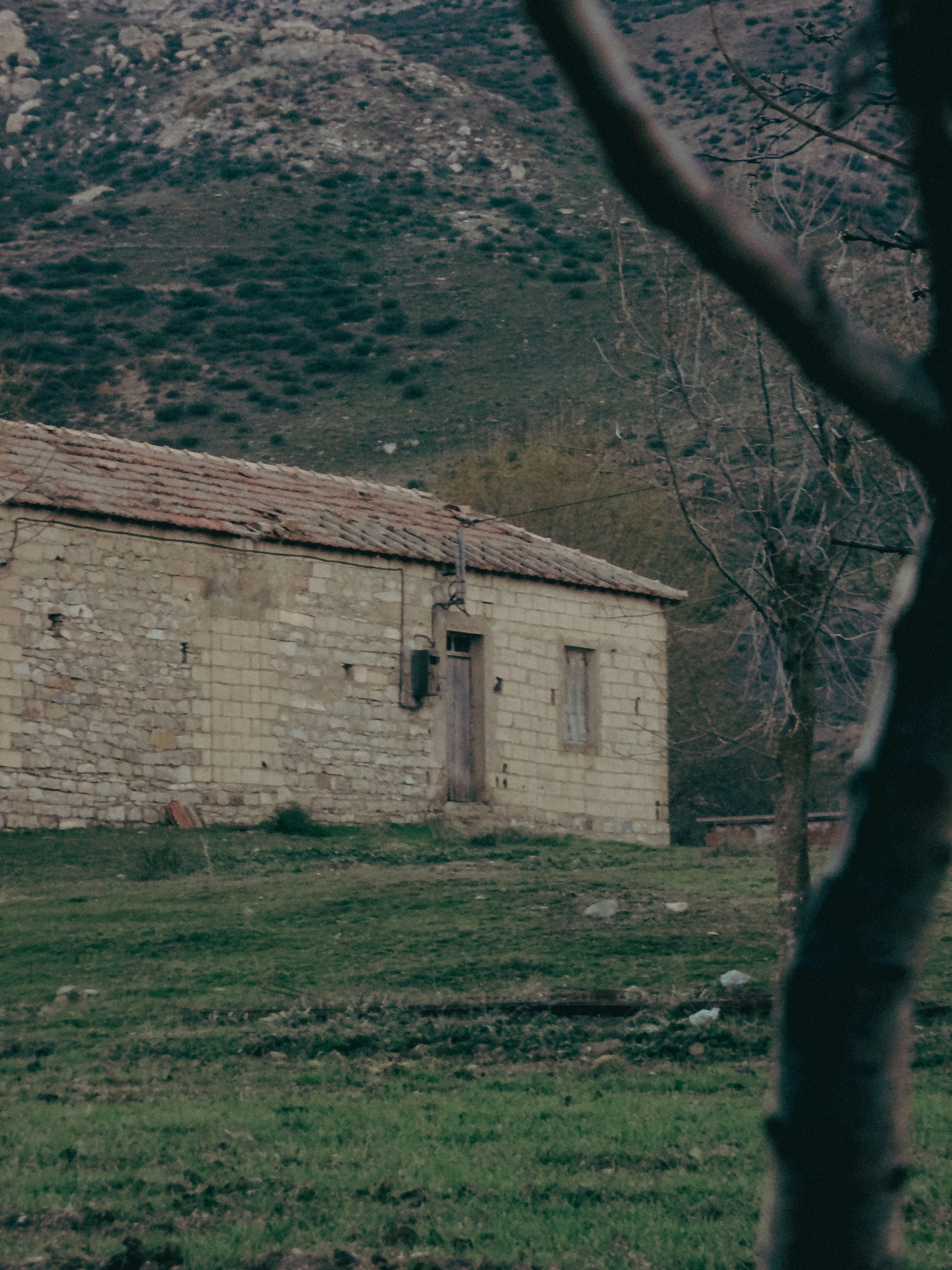 An old brick building in a field with mountains in the background