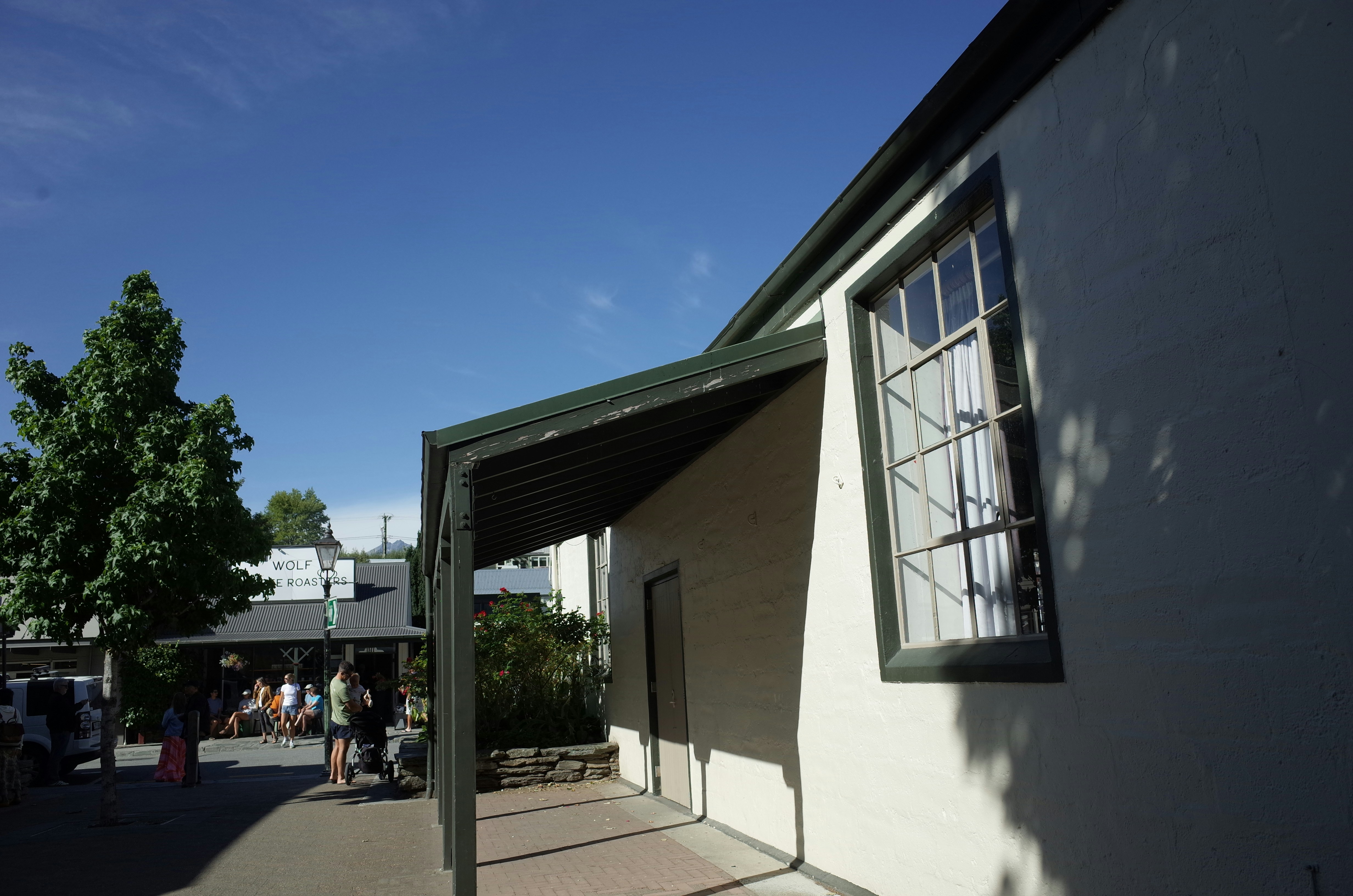 A white building with a green awning next to a sidewalk