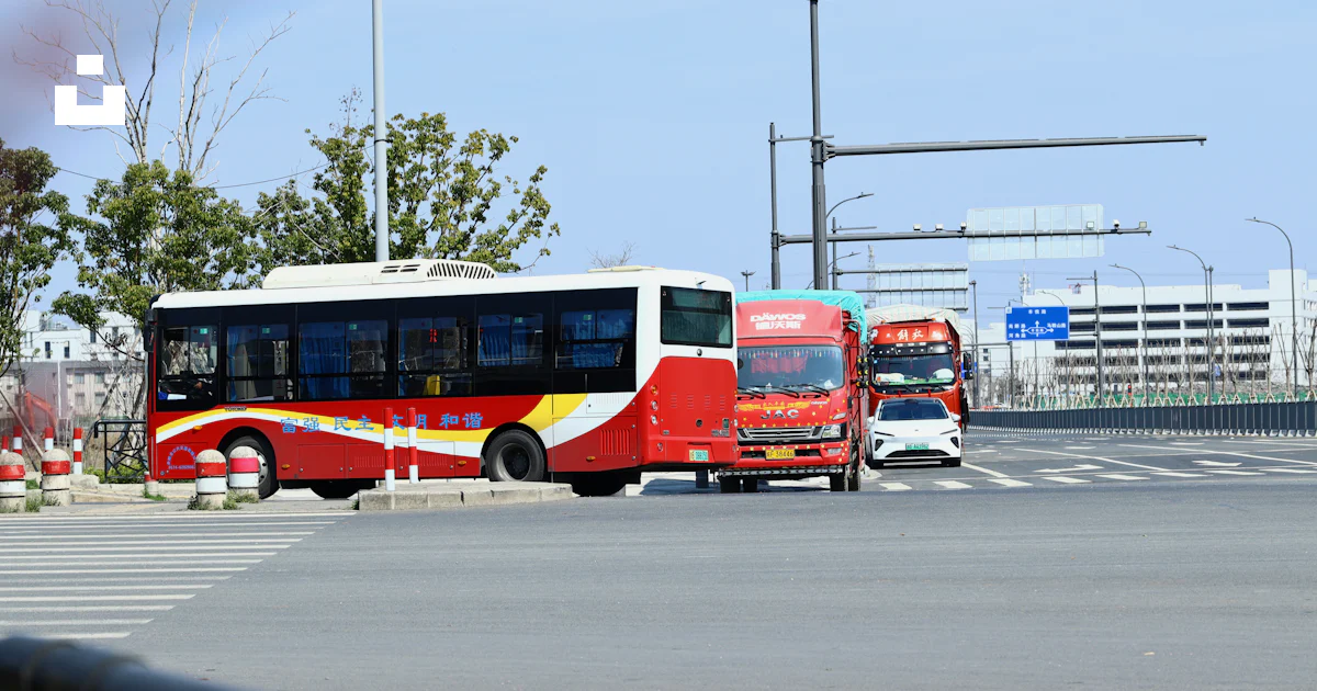 A red and yellow bus driving down a street photo – Free Car Image on ...