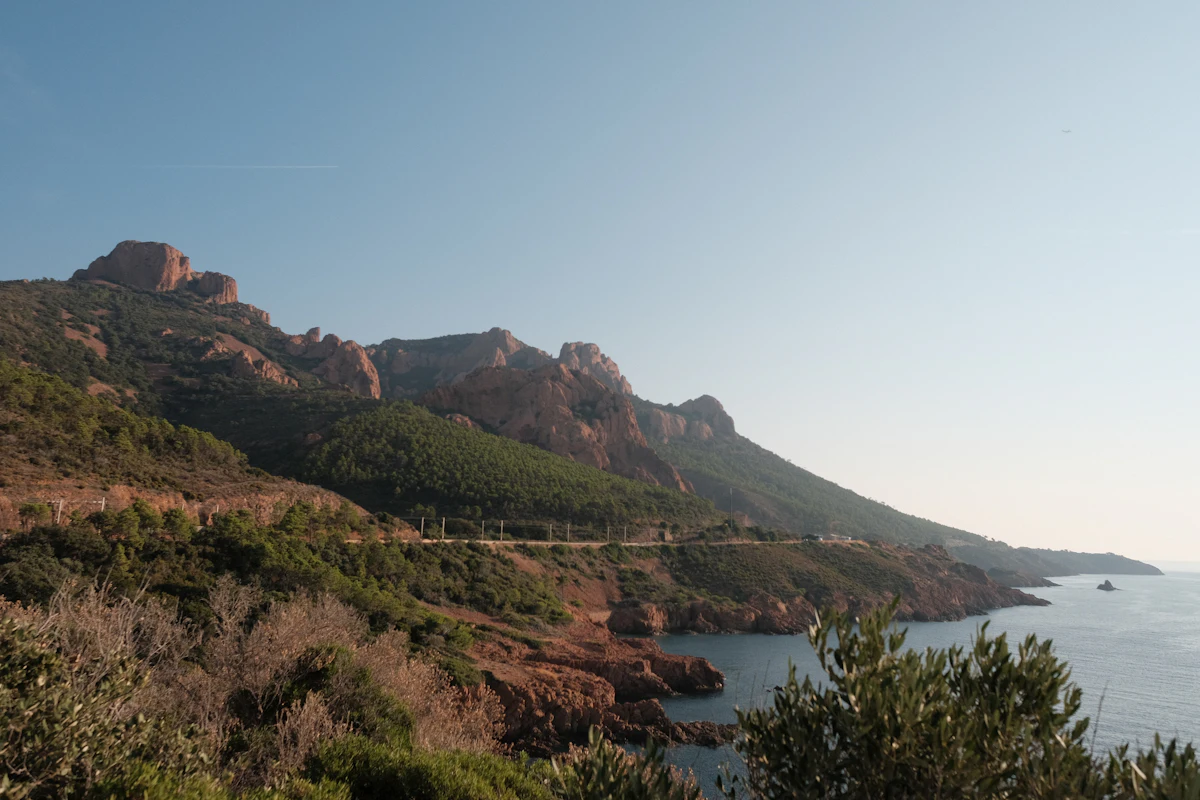 Red rock ridges and green slopes running down to the sea near Fréjus
