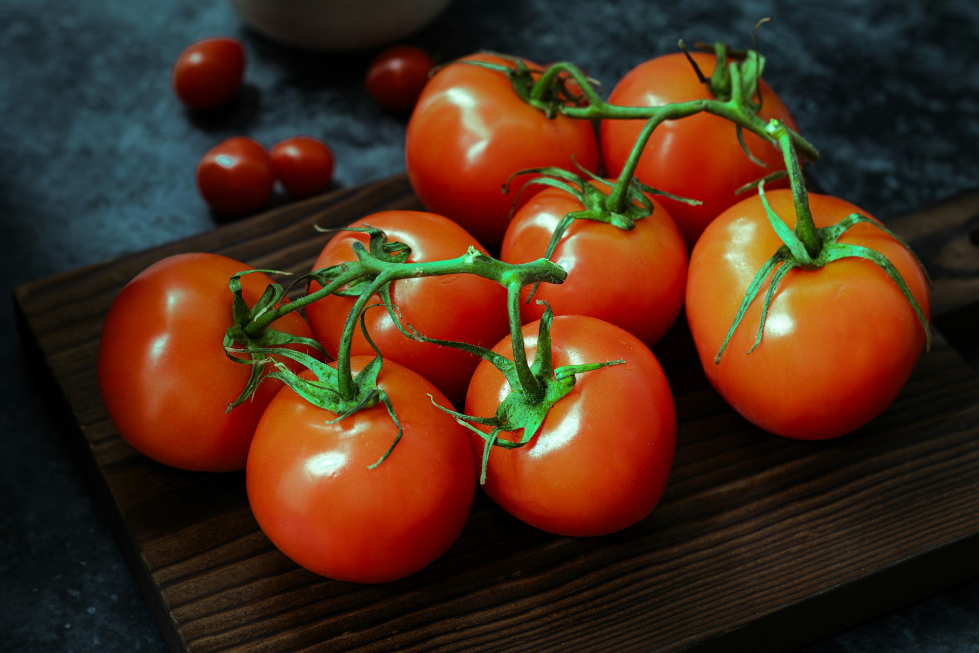 A bunch of tomatoes sitting on a cutting board