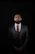 A man in a suit and tie standing in the dark