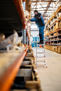 A man standing on a ladder in a warehouse